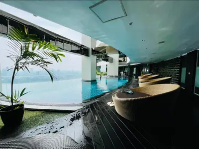 a hotel lobby with a pool with chairs and a palm tree at Gramercy Residences Spacious 1 BR Loft FREE Amenities in Manila