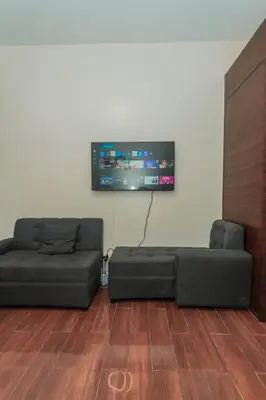 a living room with a couch and a flat screen tv at The Quirk Inn Air residence Makati Swim Gym Park Eat Laugh 3301 in Manila