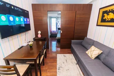 a living room with a couch and a table and a television at Urban Hideaway Cozy Makati Giggles Swim Gym Park Laugh Eat 3352 in Manila