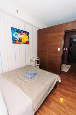 a bedroom with a bed and a painting on the wall at Urban Hideaway Cozy Makati Giggles Swim Gym Park Laugh Eat 3352 in Manila