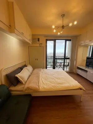 a bedroom with a large bed and a balcony at Grand Soho Makati Condo in Manila