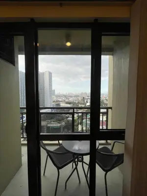 a balcony with a table and chairs and a view of a city at Grand Soho Makati Condo in Manila