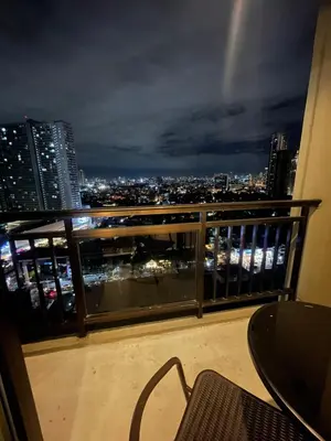 a balcony with a view of a city at night at Grand Soho Makati Condo in Manila