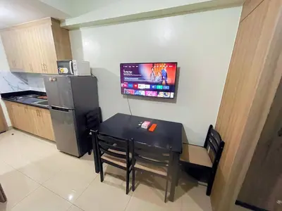 a kitchen with a table and a television on the wall at shore 2 tower 3 4 floor in Manila
