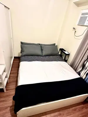 a bed with black and white sheets in a room at Emmanuel's Lair Prisma Residences in Manila