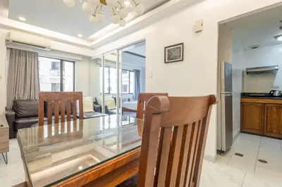 a dining room and living room with a glass table and chairs at Central BGC Forbeswood Heights in Manila