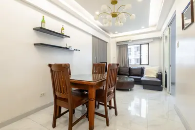 a dining room with a table and chairs and a couch at Central BGC Forbeswood Heights in Manila