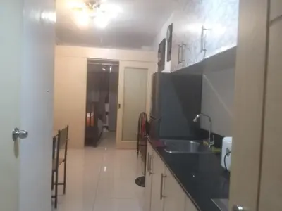 a kitchen with a sink and a black counter top at Staycation at MALL OF ASIA -by Tess Ualat in Manila