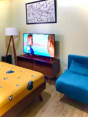 a living room with a bed and a flat screen tv at Cozy Comfy stay, tiny suite in Nuvali, SouthForbes in Silang