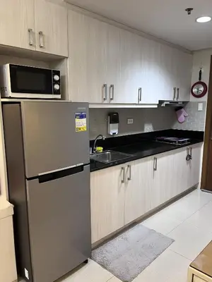 a kitchen with a refrigerator and a microwave at EaseStay by Bren in Shell Residences MOA in Manila