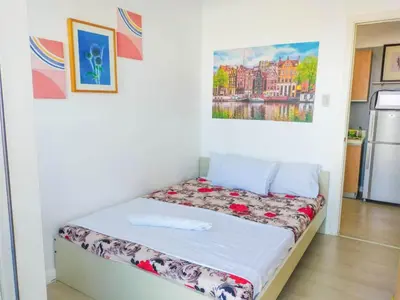 a bed in a room with a painting on the wall at Azure Condo by arlene in Manila