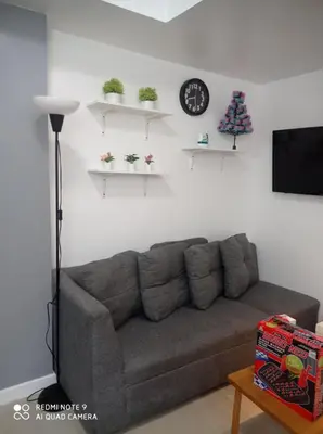 a living room with a couch and a clock on the wall at Azure place by arlene in Manila