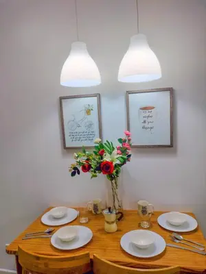 a wooden table with plates and a vase of flowers at Azure place by arlene in Manila