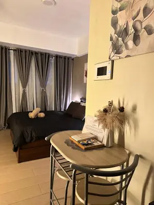 a bedroom with a bed and a table in front of a room at The Chic Studio at 150 Near NAIA Terminal 3 in Manila