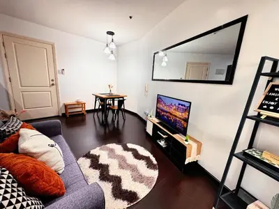 a living room with a couch and a large mirror at The Gramercy Residences NEW Sleek 1BR Suite, 600mbps Wifi, Netflix & FREE Amenities in Manila