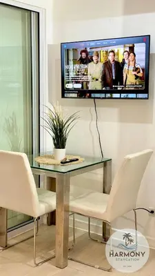 a dining room with a glass table and a tv on the wall at Azure Residences Staycation - Bahamas tower in Manila