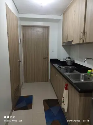 a kitchen with wooden cabinets and a sink and a door at Shore 2 Residence Tower 3 in Manila