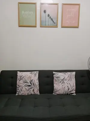 a black couch against a white wall with three pictures at Shore 2 Residence Tower 3 in Manila