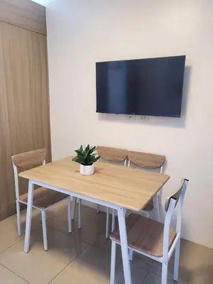 a wooden table with chairs and a tv on a wall at Barkada Pamilya BnB by Metro Staycation in Manila