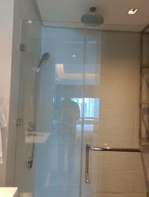 a shower with a glass door in a bathroom at Alphaland Suites Apartment Hotel in Manila