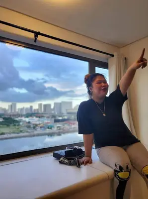 a woman sitting on a window sill with her arm up at Group Stay by Metro Staycation in Manila