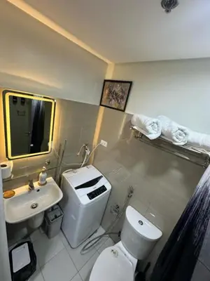 a bathroom with a white toilet and a sink at One Bedroom Apartment near MOA in Manila