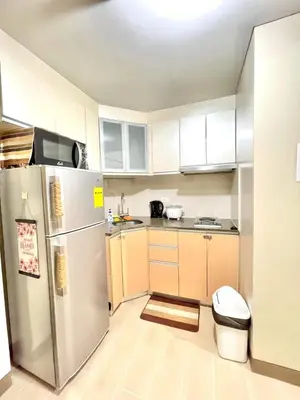 a kitchen with white cabinets and a stainless steel refrigerator at ASD Airport Condotel Pasay in Manila