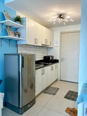 a kitchen with a stainless steel refrigerator and white cabinets at Jazz Residences Makati Tower B in Manila