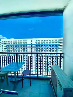 a balcony with a table and a bench and a building at Sea residences by mavis in Manila