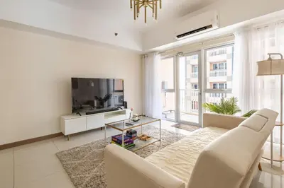 a living room with a couch and a tv at Minimalist Haven 3BR unit at Mckinley Hill in Manila