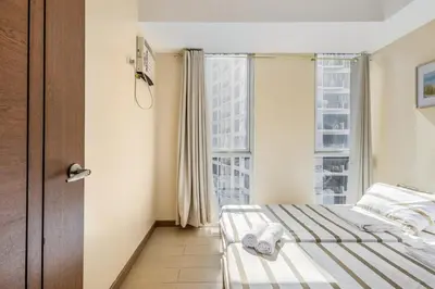 a hotel room with a bed and a window at Minimalist Haven 3BR unit at Mckinley Hill in Manila
