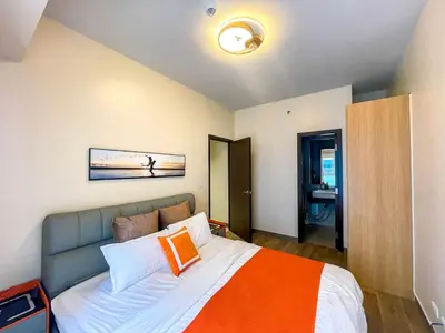 a bedroom with a bed with an orange and white blanket at Cozy 2BR Suite near Airport & Okada, Infinity Pool in Manila