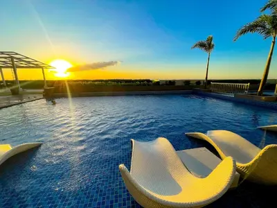 a pool with chairs and the sunset in the background at Spacious 1BR Suite near Okada, Solaire, Airport in Manila
