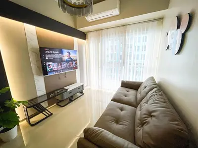 a living room with a couch and a flat screen tv at Spacious 1BR Suite near Okada, Solaire, Airport in Manila