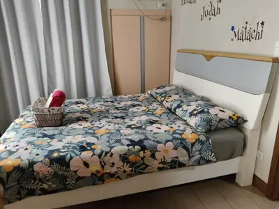 a small bedroom with a bed with a floral comforter at LDN Two Palm Tree Villa LFamilia in Manila