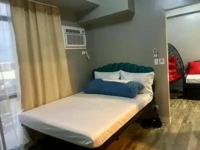 a bed with a blue headboard in a room at 1 BR Executive Suite Gentry Manor by JMS in Manila