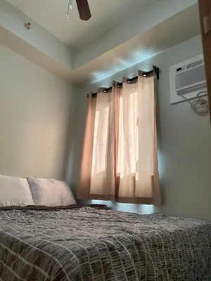 a bedroom with a bed and a window at Charm Residences Building E in Manila