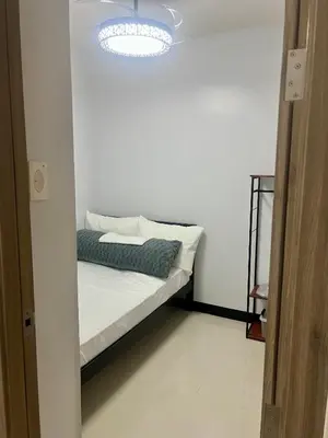 a white room with a bed with a light at 1 Br Family Suite in S Residences by JMS in Manila