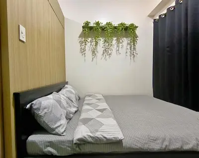 a bedroom with a bed with a plant on the wall at Shore Residences MOA Minimalist Room in Manila