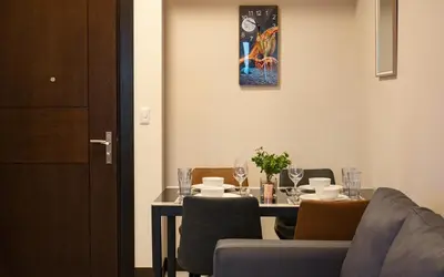 a dining room with a table with chairs and a table and a painting at Cozy 2BR Suite in Uptown BGC with PS4 and walking distance to Malls and Restaurants in Manila