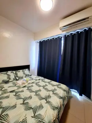 a bedroom with a bed and a window with blue curtains at Wooden style amenities view in Manila