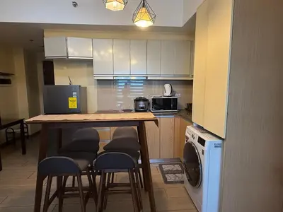 a kitchen with a table with chairs and a washer at Deluxe Suite in Venice Mall in Manila