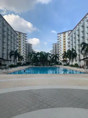 a large swimming pool with palm trees and buildings at PEACETIME CONDO FIELD RESIDENCES BLDG 6 u1006B in Manila
