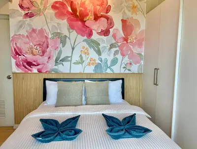 a bedroom with a bed with blue bow pillows on it at Spacious Tropics with Golf View in BGC in Manila