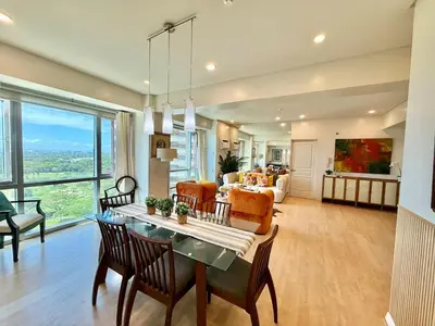 a living room with a table and chairs and a couch at Spacious Tropics with Golf View in BGC in Manila