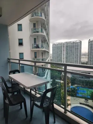 a table and chairs on a balcony with a view of a building at Azure Staycation Philippines by AMRS Near Manila International Airport in Manila