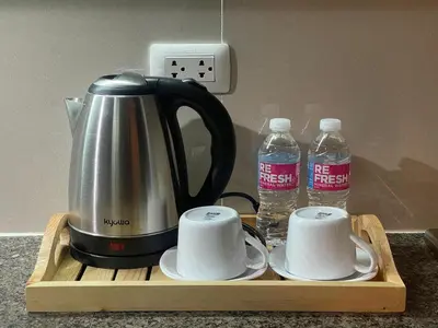 a coffee maker and two bottles of water on a wooden tray at NAIA Terminal 3 Condo Newport with WIFI Netflix Pool in Manila