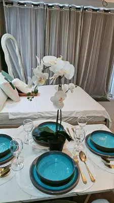 a white table with blue plates and flowers on it at Cozy Apartment Azure Urban Resort Residences in Manila