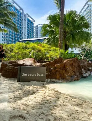a sign on a beach with palm trees and buildings at Azure Urban Resort Residences - Staycationary Miami 1710 in Manila