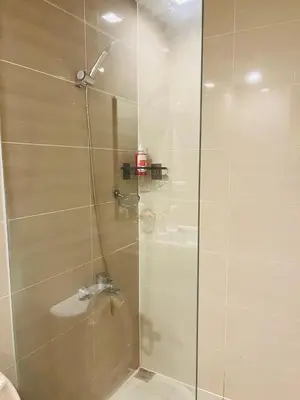 a shower with a glass door with a sink at BGC Simple Elegant 300Mbps Wifi,Pool,Netflix in Manila